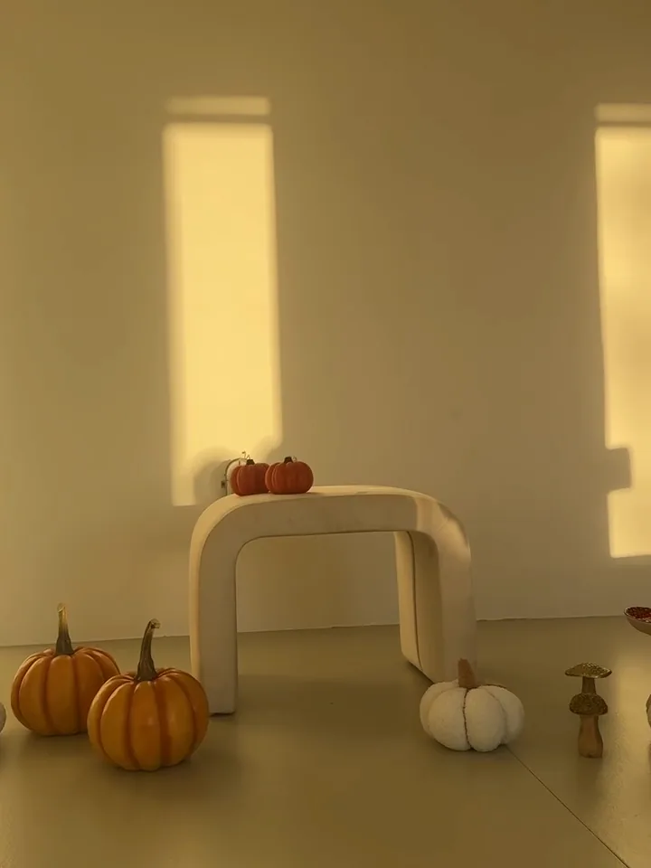Bílá stěna s pruhy světla z oken a dýně na podlaze